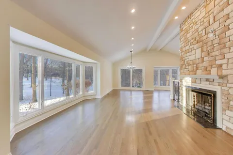 an empty room with wooden floor fireplace and windows