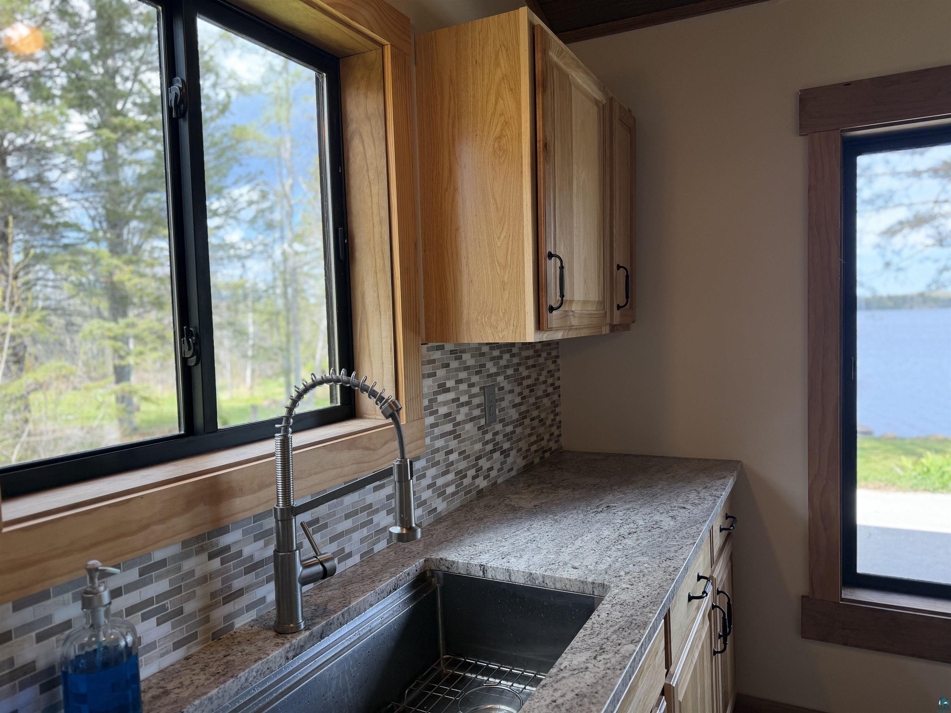 5274 Marble Lake Road Two Harbors, MN 55616 - Photo 18 of 79 Kitchen featuring wood cabinetry, light-colored granite countertops, and a mosaic tile backsplash
