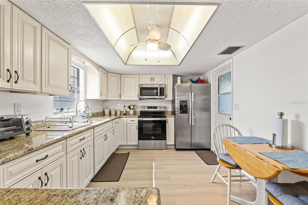 8306 Needles Drive Hudson, FL 34667 - Photo 14 of 39 a large kitchen with stainless steel appliances granite countertop a stove a sink dishwasher and a refrigerator with white cabinets