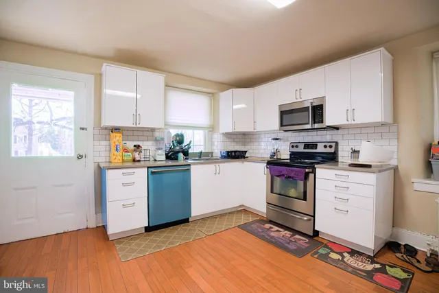 a kitchen with stainless steel appliances a stove top oven a sink a window and white cabinets