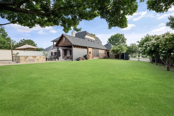 a view of a house next to a big yard and large trees