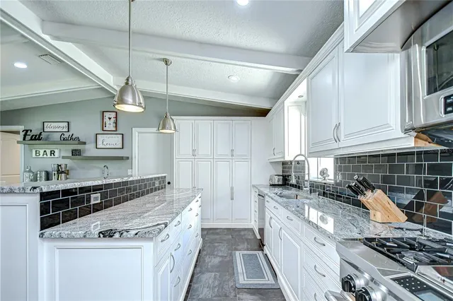 a kitchen with granite countertop a sink stainless steel appliances and white cabinets