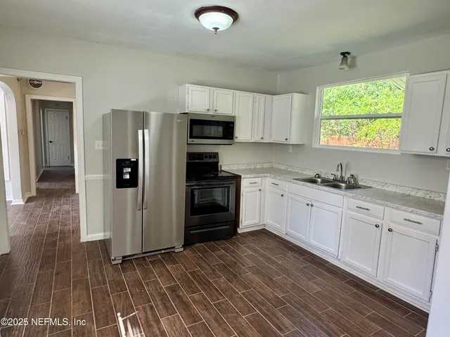 a kitchen with granite countertop a refrigerator and a stove top oven