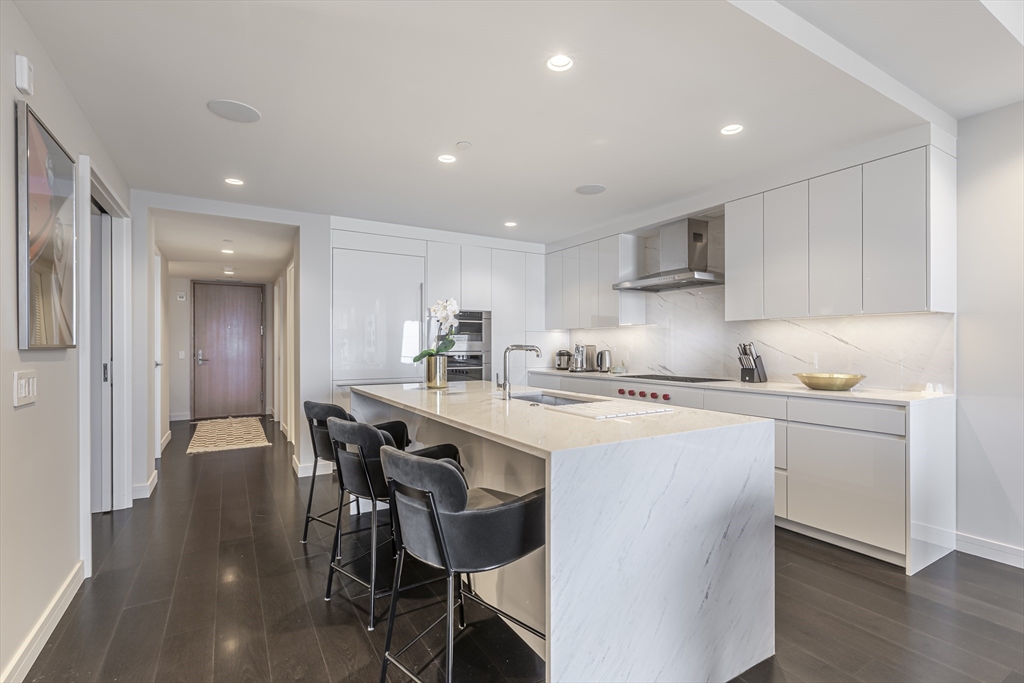 150 Seaport Boulevard, Unit 6D Boston, MA 02210 - Photo 13 of 30 a kitchen with a dining table chairs wooden floor cabinets and appliances