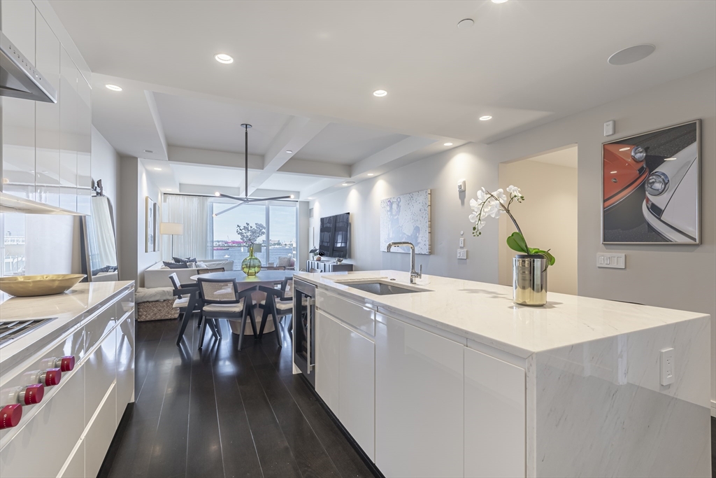 150 Seaport Boulevard, Unit 6D Boston, MA 02210 - Photo 6 of 30 a room with stainless steel appliances kitchen island granite countertop lots of white furniture a sink a stove a dining table and chairs