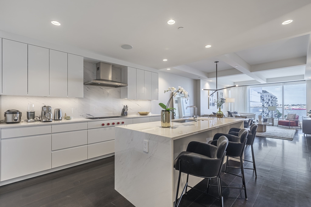 150 Seaport Boulevard, Unit 6D Boston, MA 02210 - Photo 7 of 30 a kitchen with stainless steel appliances a table and chairs in it