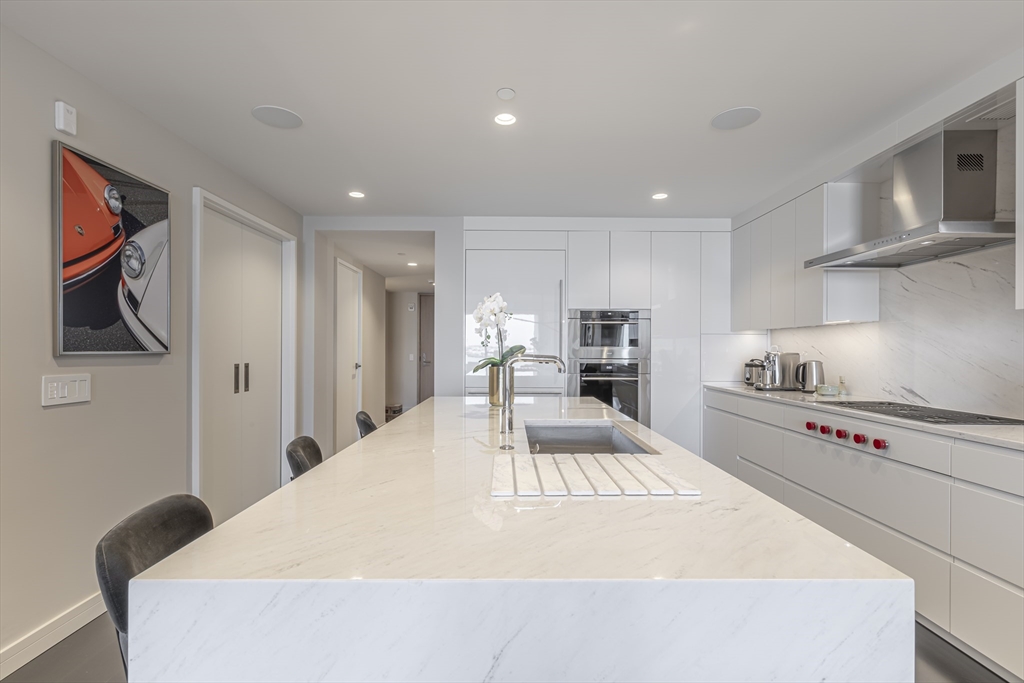150 Seaport Boulevard, Unit 6D Boston, MA 02210 - Photo 9 of 30 a kitchen with stainless steel appliances a stove a refrigerator white cabinets and wooden floor