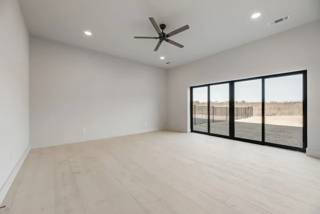 an empty room with windows and ceiling fan