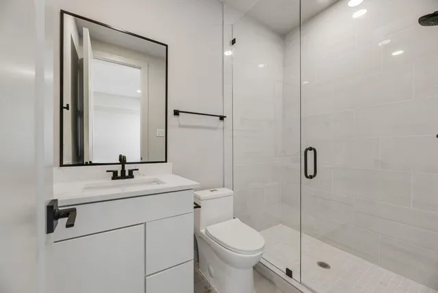 a bathroom with a shower sink vanity mirror and toilet