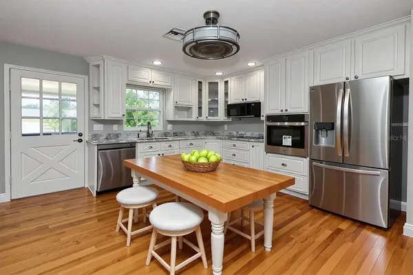 a kitchen with stainless steel appliances a dining table chairs stove refrigerator and microwave