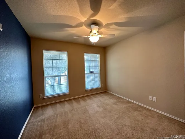 an empty room with windows and ceiling fan