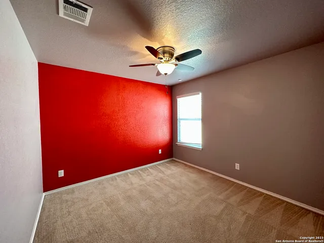an empty room with windows and fan