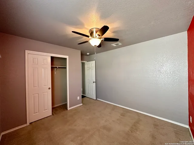 an empty room with closet and a chandelier fan