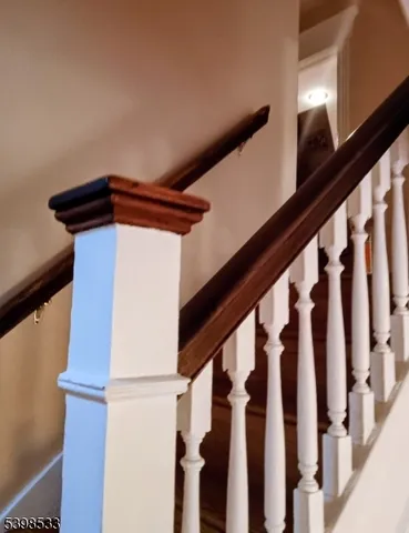 a view of a hallway to a livingroom with wooden floor and furniture