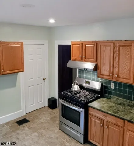 a kitchen with granite countertop a stove sink and cabinets