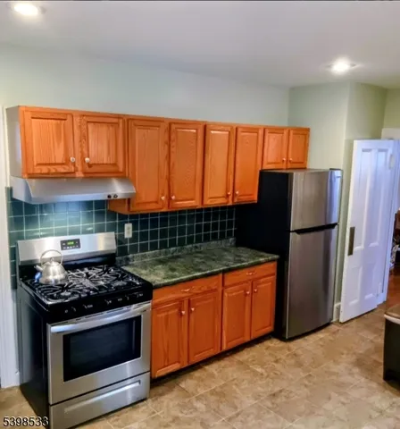 a kitchen with stainless steel appliances granite countertop a stove a refrigerator and a stove top oven
