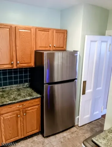 a kitchen with stainless steel appliances granite countertop a refrigerator and a wooden cabinets