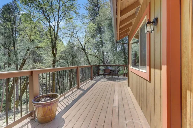 a balcony with wooden floor and trees in the back