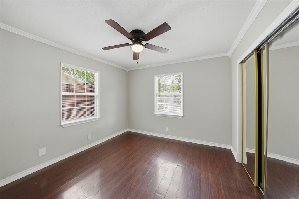 1108 Billie Ruth Lane Hurst, TX 76053 - Photo 17 of 27 Room featuring dark wood-finish flooring, two large windows with blinds, a ceiling fan with light fixture, and a mirrored sliding closet door