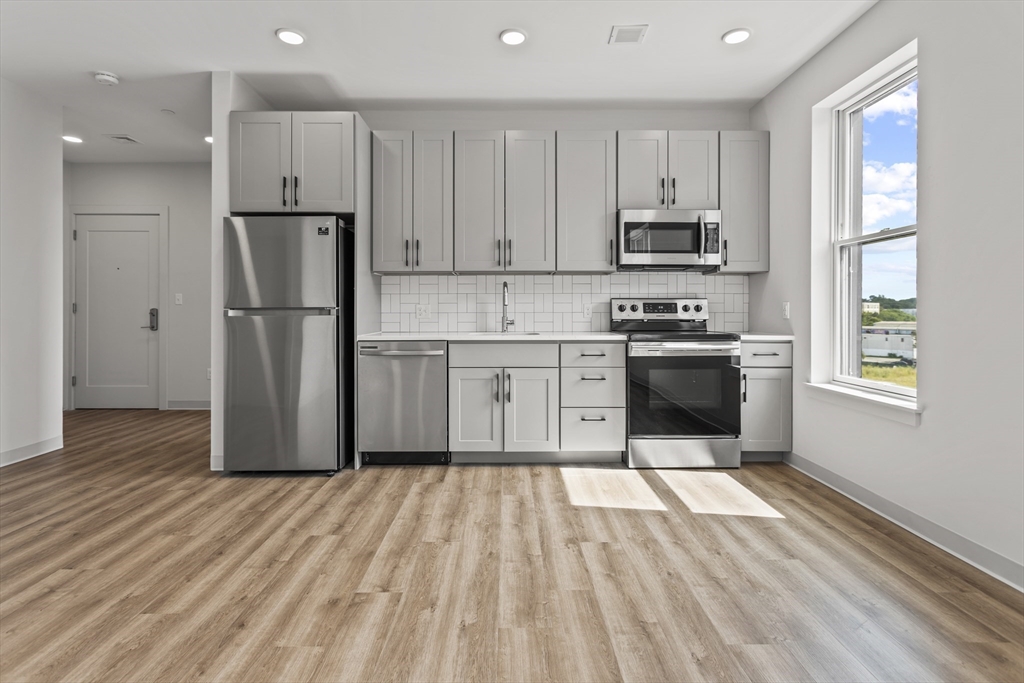 a kitchen with wooden floors and white stainless steel appliances