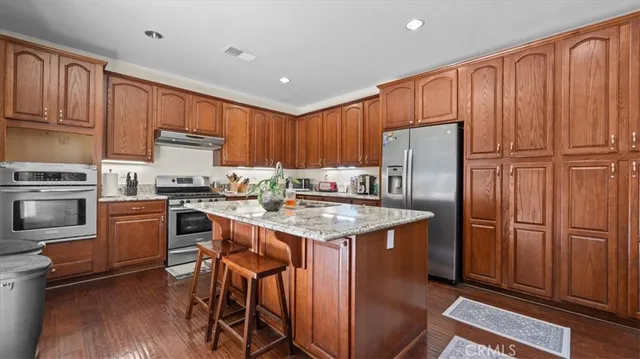 a kitchen with kitchen island granite countertop a refrigerator stove and oven