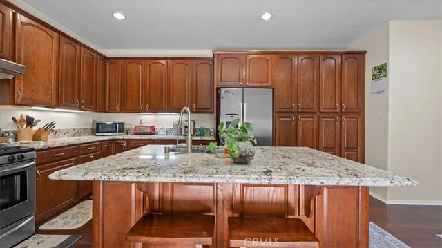a kitchen with stainless steel appliances granite countertop a sink refrigerator and cabinets