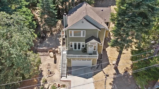 an aerial view of a house with a yard and covered with trees