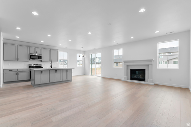 1869 South 2425 West Ogden, UT 84401 - Photo 22 of 22 Kitchen featuring open floor plan, gray cabinets, a kitchen island with sink, light countertops, and hanging lights