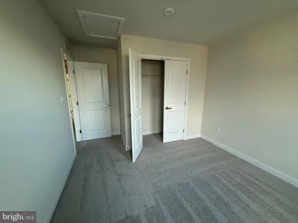 a view of an empty room with closet and wooden door