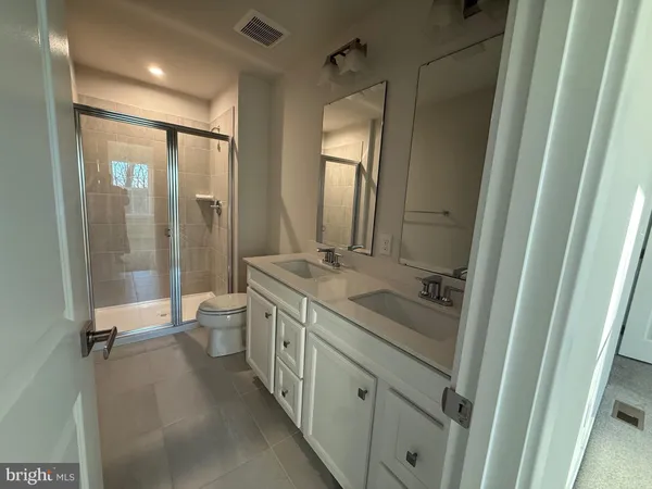 a bathroom with a double vanity sink toilet mirror and shower