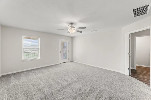 an empty room with windows and ceiling fan