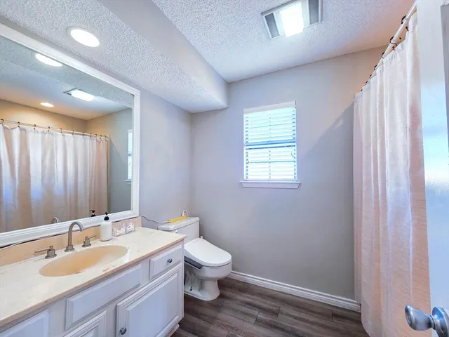 a bathroom with a granite countertop sink toilet and mirror