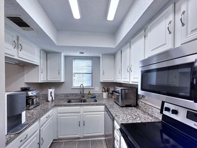 a kitchen with stainless steel appliances granite countertop a sink dishwasher stove and microwave with wooden cabinets