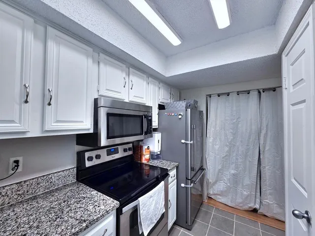 a kitchen with granite countertop a stove a refrigerator and cabinets