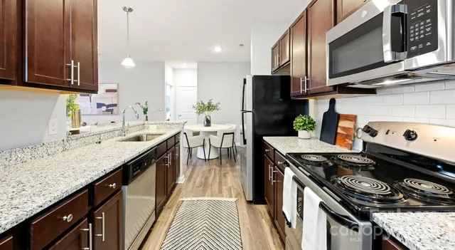 a kitchen with stainless steel appliances granite countertop a stove a sink dishwasher and a microwave with wooden floor