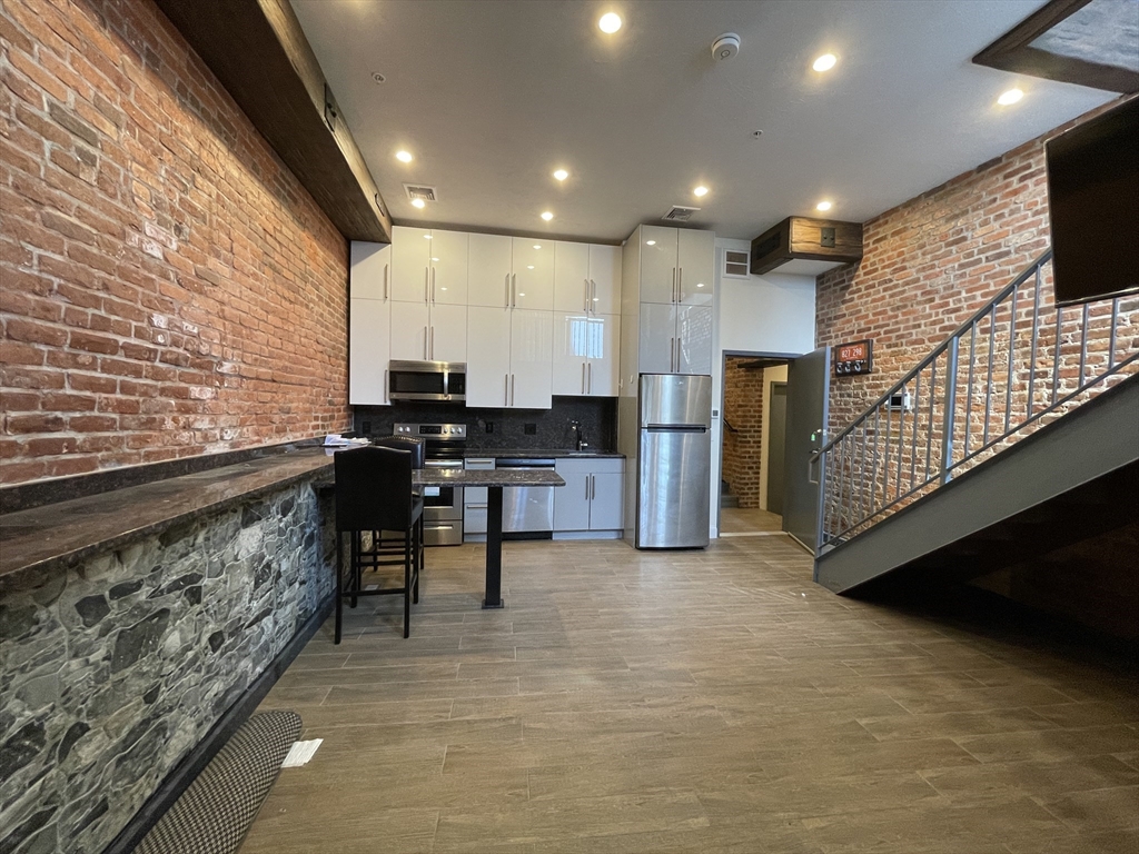 1028 Commonwealth Avenue, Unit 102 Boston, MA 02215 - Photo 2 of 11 a kitchen with stainless steel appliances kitchen island granite countertop a stove a refrigerator a sink and a microwave
