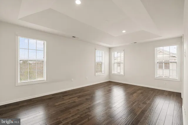 a view of an empty room with wooden floor and window