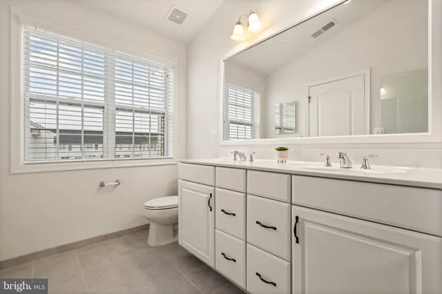 a bathroom with double sink a toilet and a window
