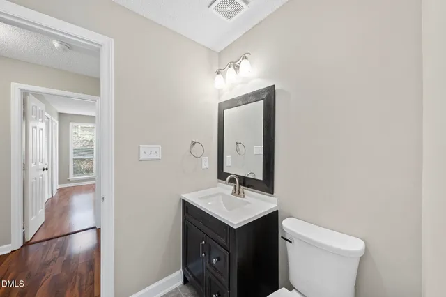 a bathroom with a toilet a sink a mirror and vanity