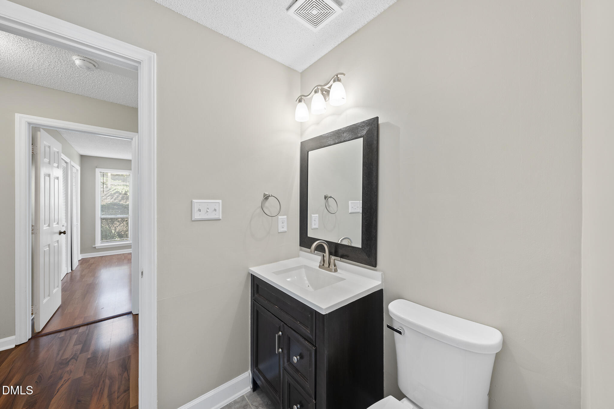 4601 Timbermill Court, Unit 104 Raleigh, NC 27612 - Photo 15 of 24 a bathroom with a toilet a sink a mirror and vanity