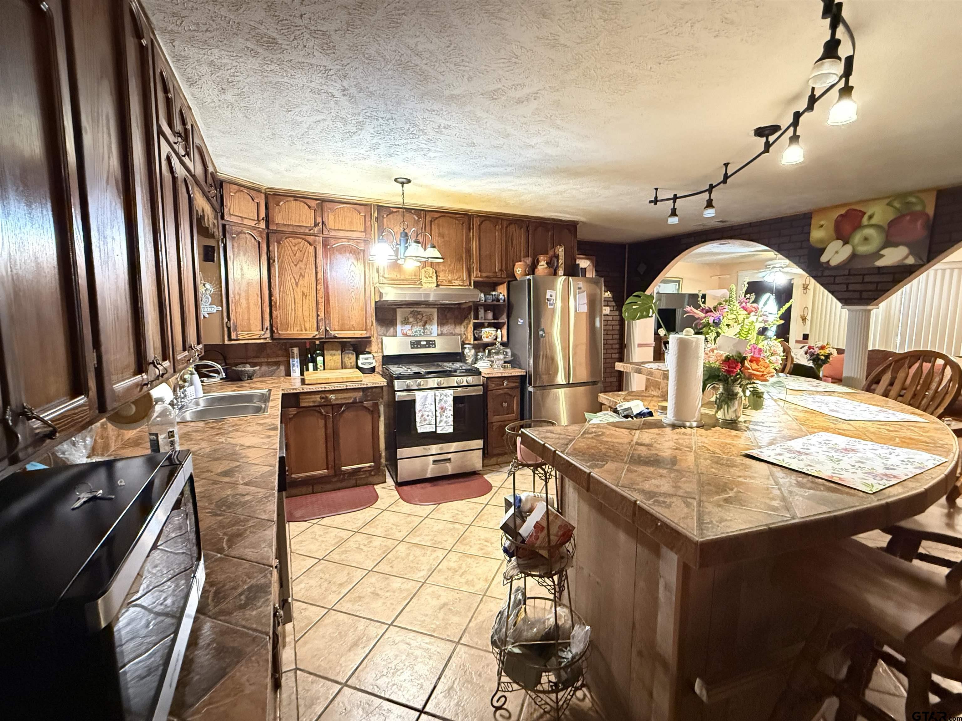 508 Whippoorwill Street Henderson, TX 75652 - Photo 9 of 24 a large kitchen with kitchen island a stove a sink dishwasher and white cabinets with wooden floor