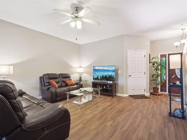 a living room with furniture a flat screen tv and a ceiling fan