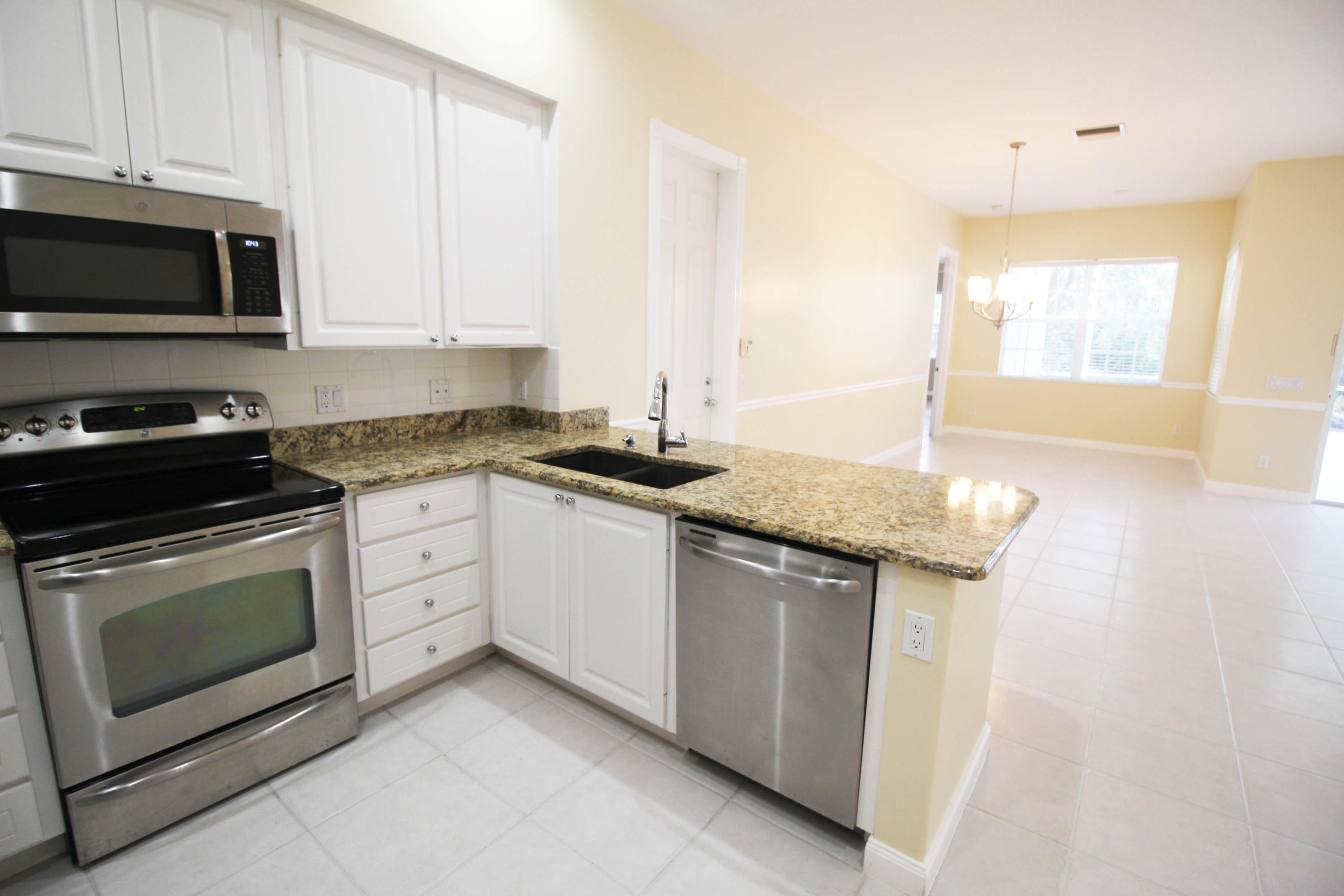 256 San Remo Drive Jupiter, FL 33458 - Photo 46 of 66 a kitchen with granite countertop a sink a stove and microwave