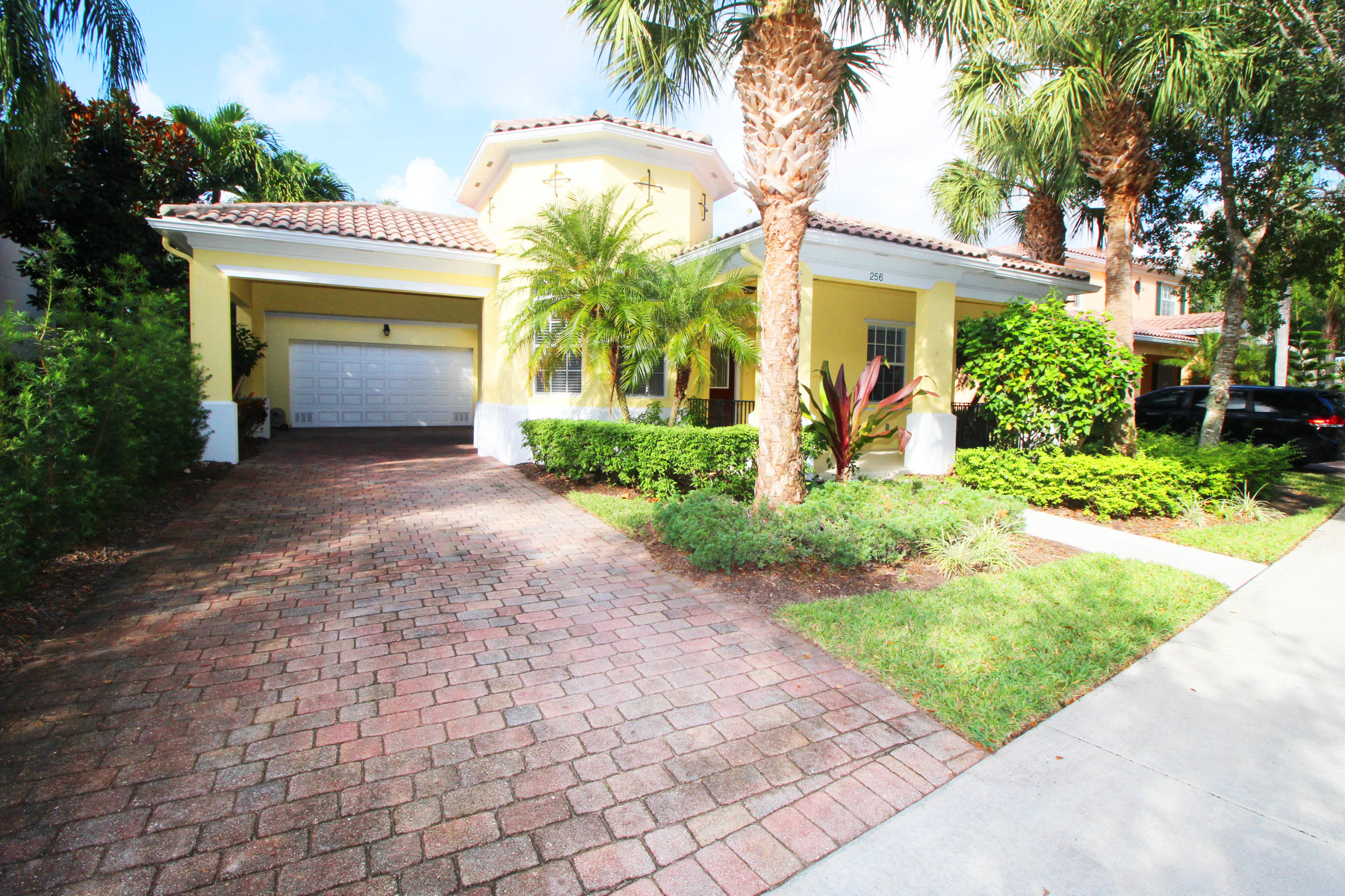 256 San Remo Drive Jupiter, FL 33458 - Photo 6 of 66 a front view of a house with a yard and potted plants