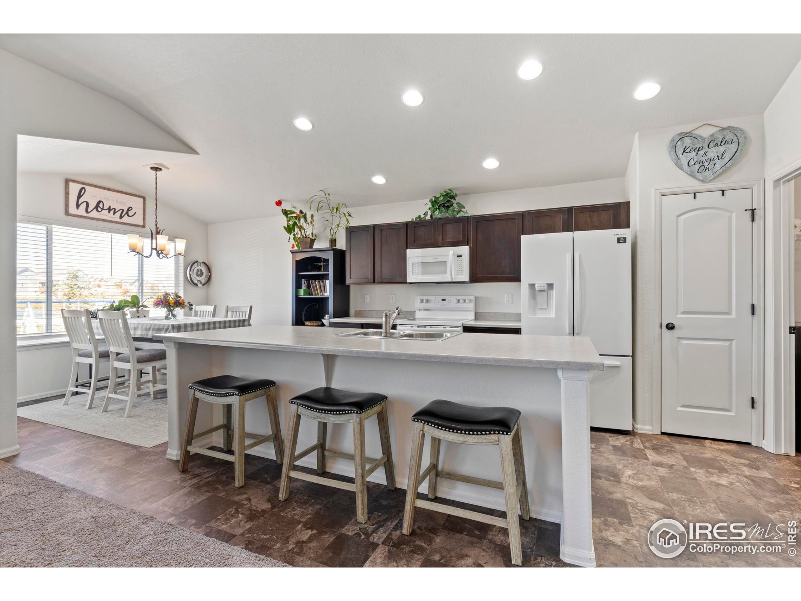 941 Barasingha Street Severance, CO 80550 - Photo 12 of 46 a kitchen with a table chairs refrigerator and cabinets