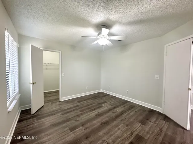 an empty room with wooden floor and ceiling fan