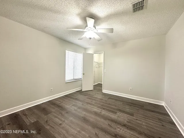 an empty room with wooden floor fan and windows