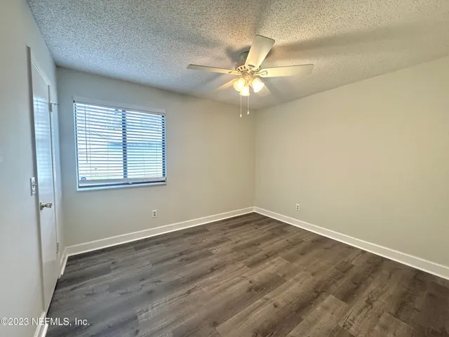 an empty room with wooden floor fan and windows