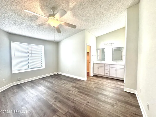 an empty room with wooden floor fan and windows