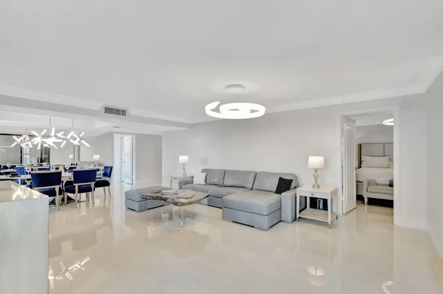 a living room with furniture kitchen view and a chandelier